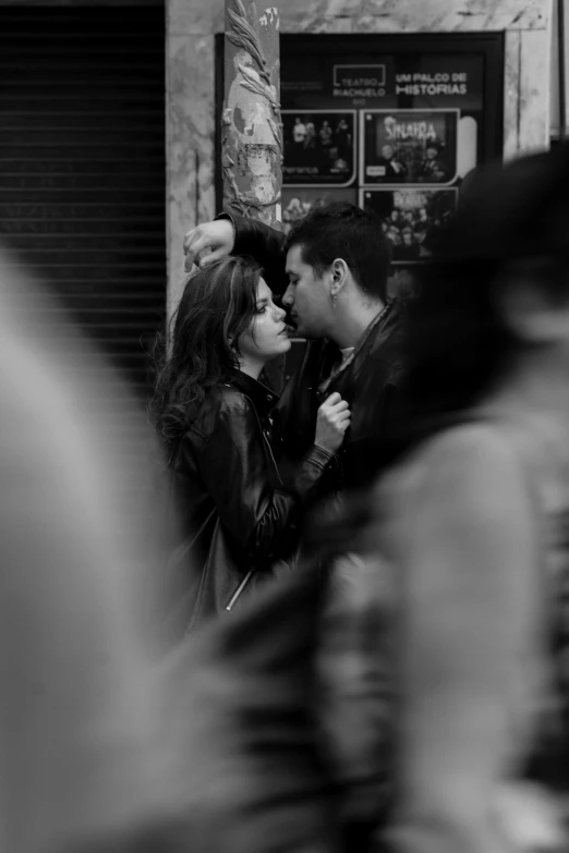 a man is kissing a woman's face while on the street