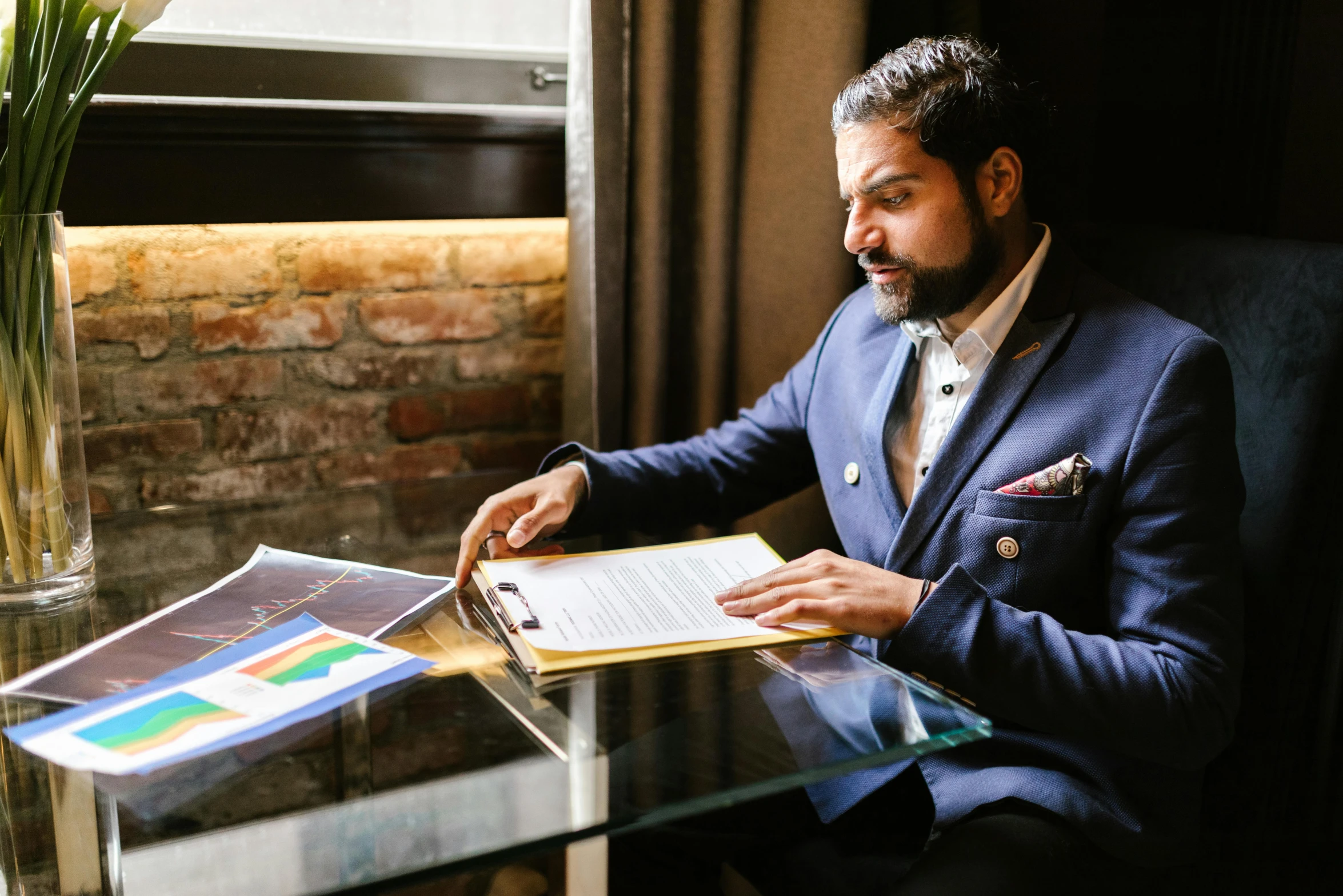 the man sitting in front of a table is looking at the paper