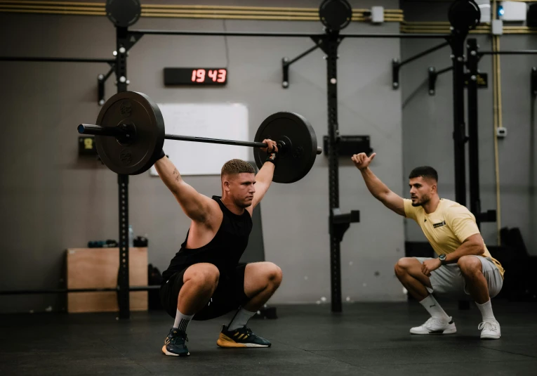 a man squats while another squattes on the ground