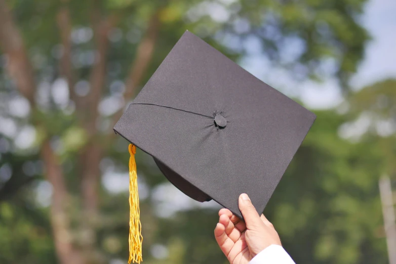 a person holds up a graduation hat to the camera