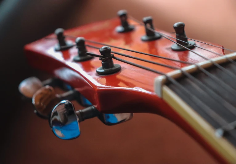 the top part of a red guitar neck with a tuner