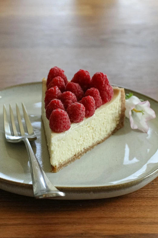 a slice of cheesecake topped with fresh raspberries on a plate