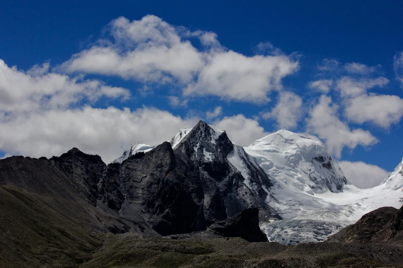 snow capped mountains with clouds above them