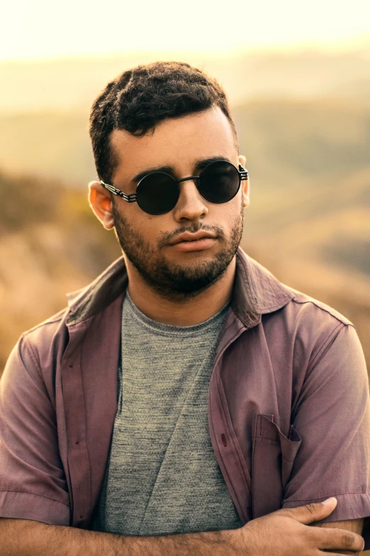 a man wearing glasses and a jacket in front of a field