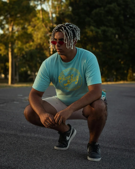 man with dreadlocks sitting on skate board wearing a light blue shirt