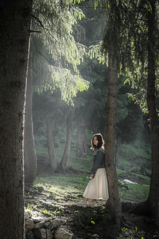 a  wearing a skirt leaning against a tree