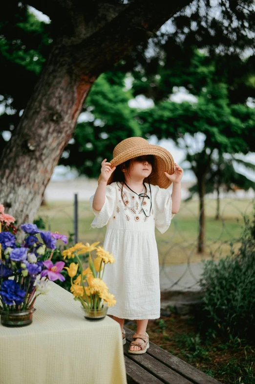 a  in a hat is standing next to flowers