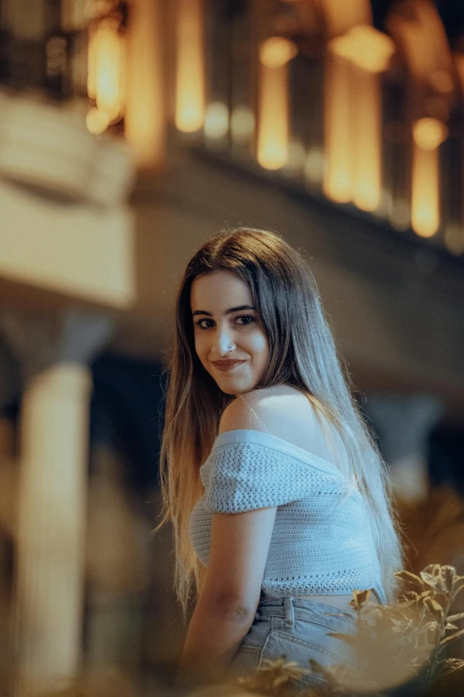 young woman with long hair standing outside of an old building