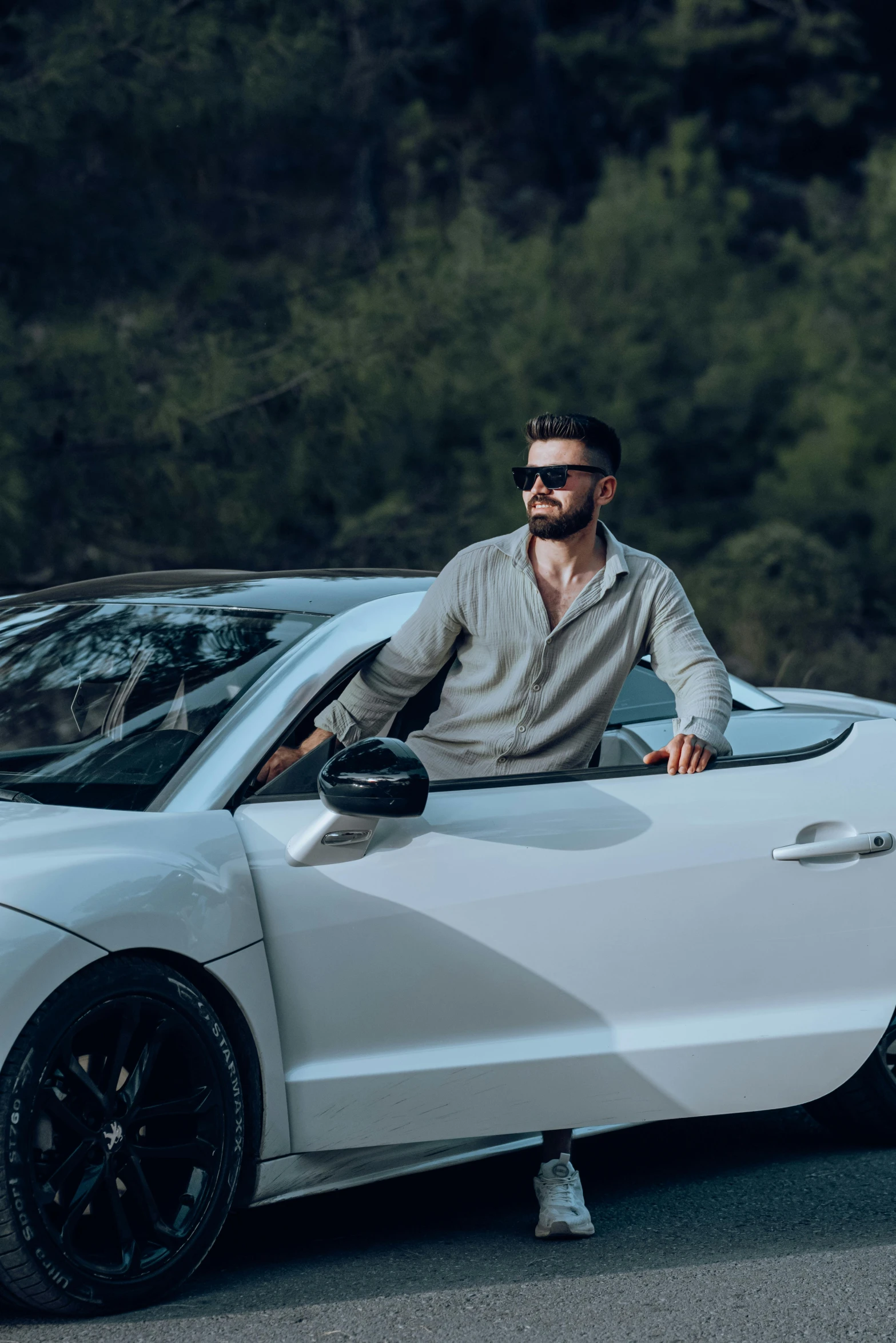 man sitting inside a white sports car on the road