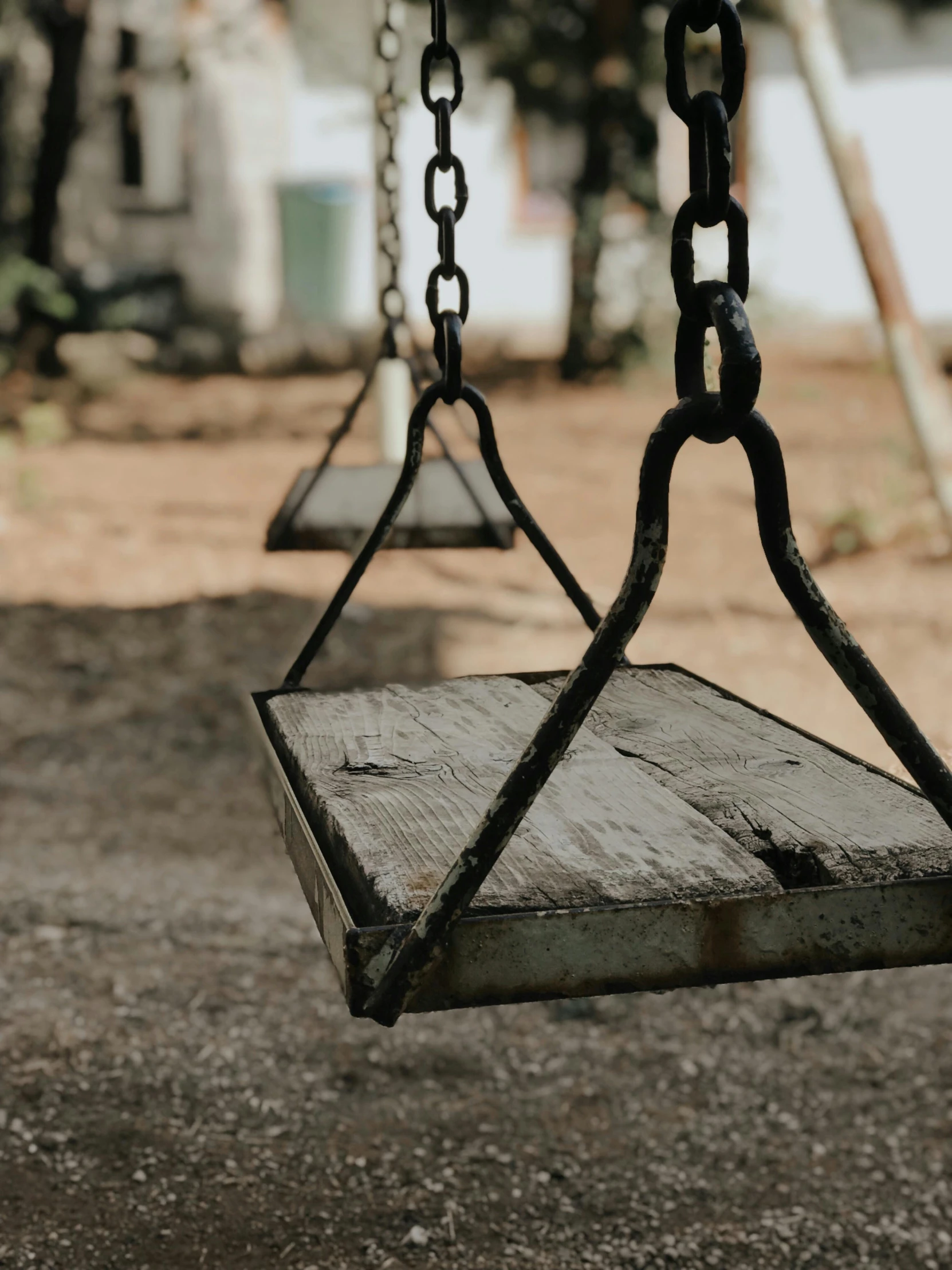 an empty wooden swing with chains hanging from it