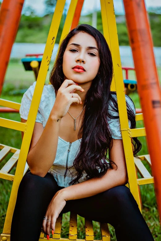 a girl sitting in a swing, posing for the camera