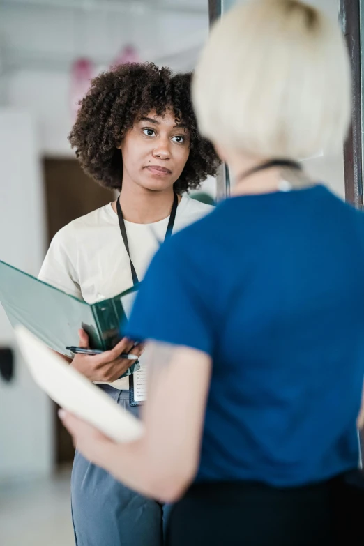 a woman with a folder talking to another woman