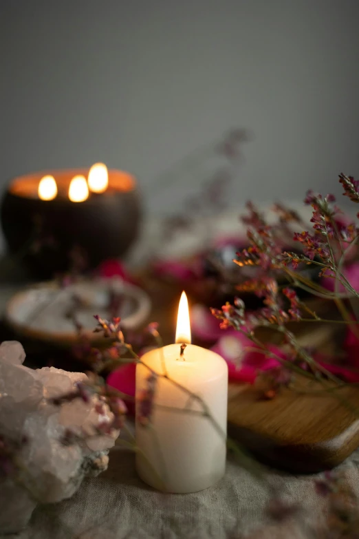 candles lit next to other flowers on a table