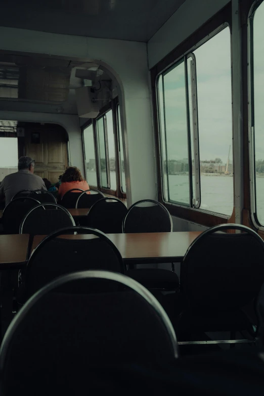 people are seen looking out of windows from the dining car on a boat