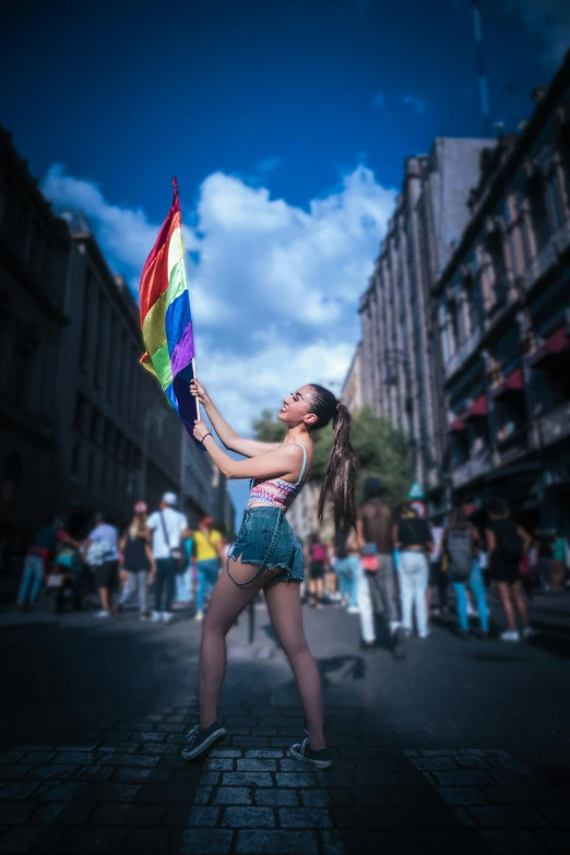 a woman holding a rainbow colored kite standing on a street