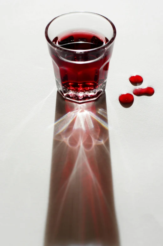 red liquid in a glass with several scattered petals