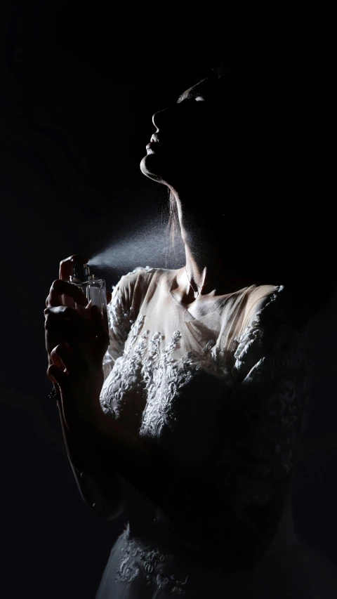 a woman wearing a gown is spraying sand on her face