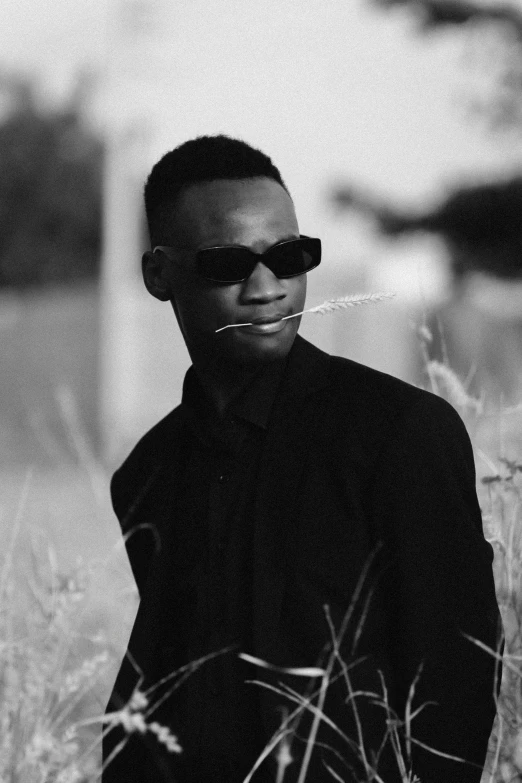 a black and white po of a man with glasses and headgear in grassy area