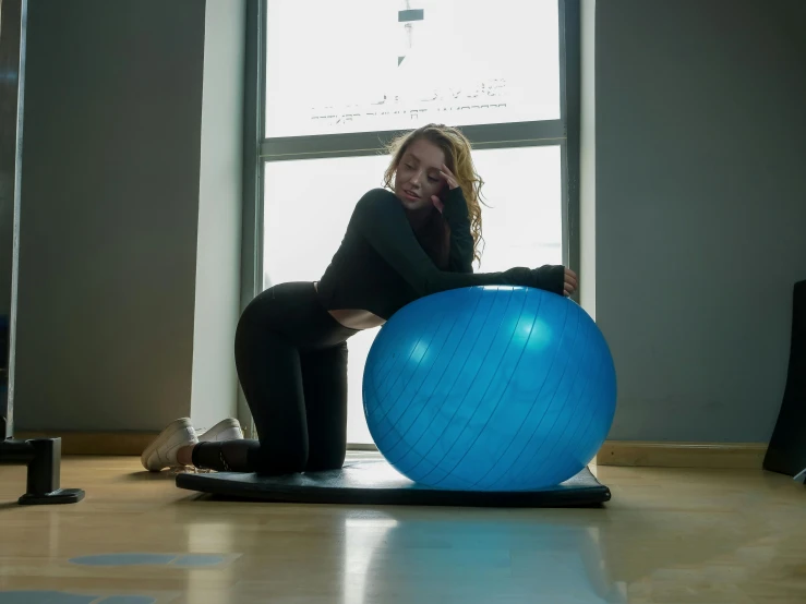 there is a woman sitting on a ball in the middle of a room