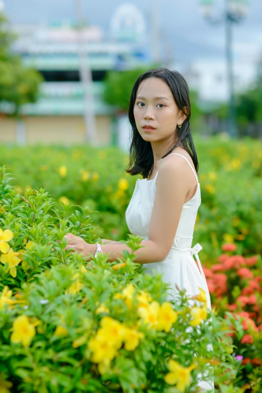 the girl is in white dress walking around flowers