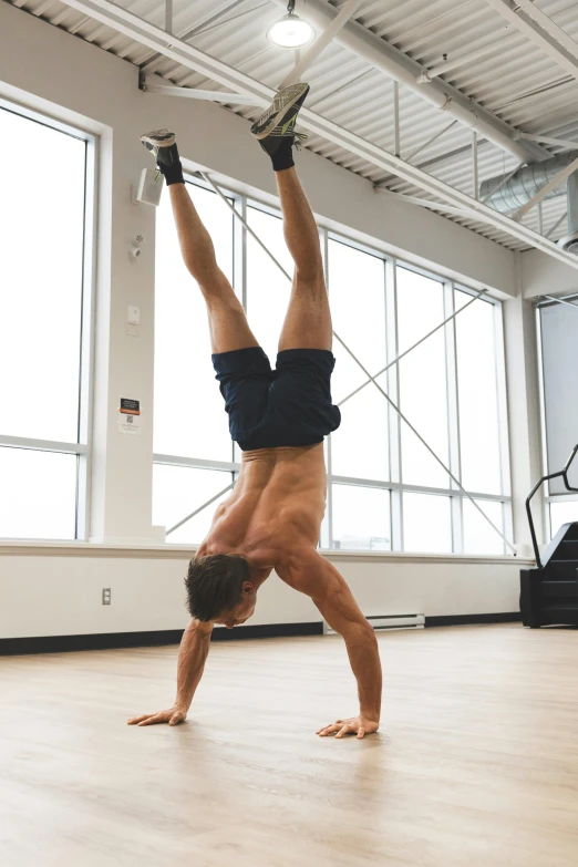 a man doing a handstand on the floor of a gym