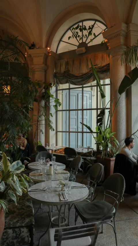 a long dining room set up for two, with round tables, and chairs