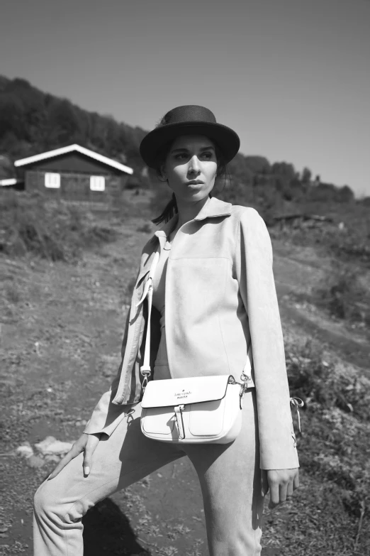 black and white po of woman in a hat holding a handbag