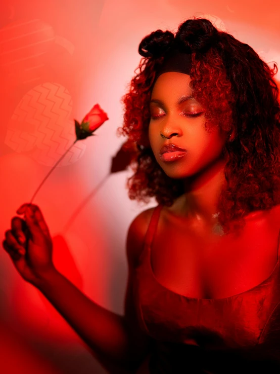 an african american woman holds a red flower