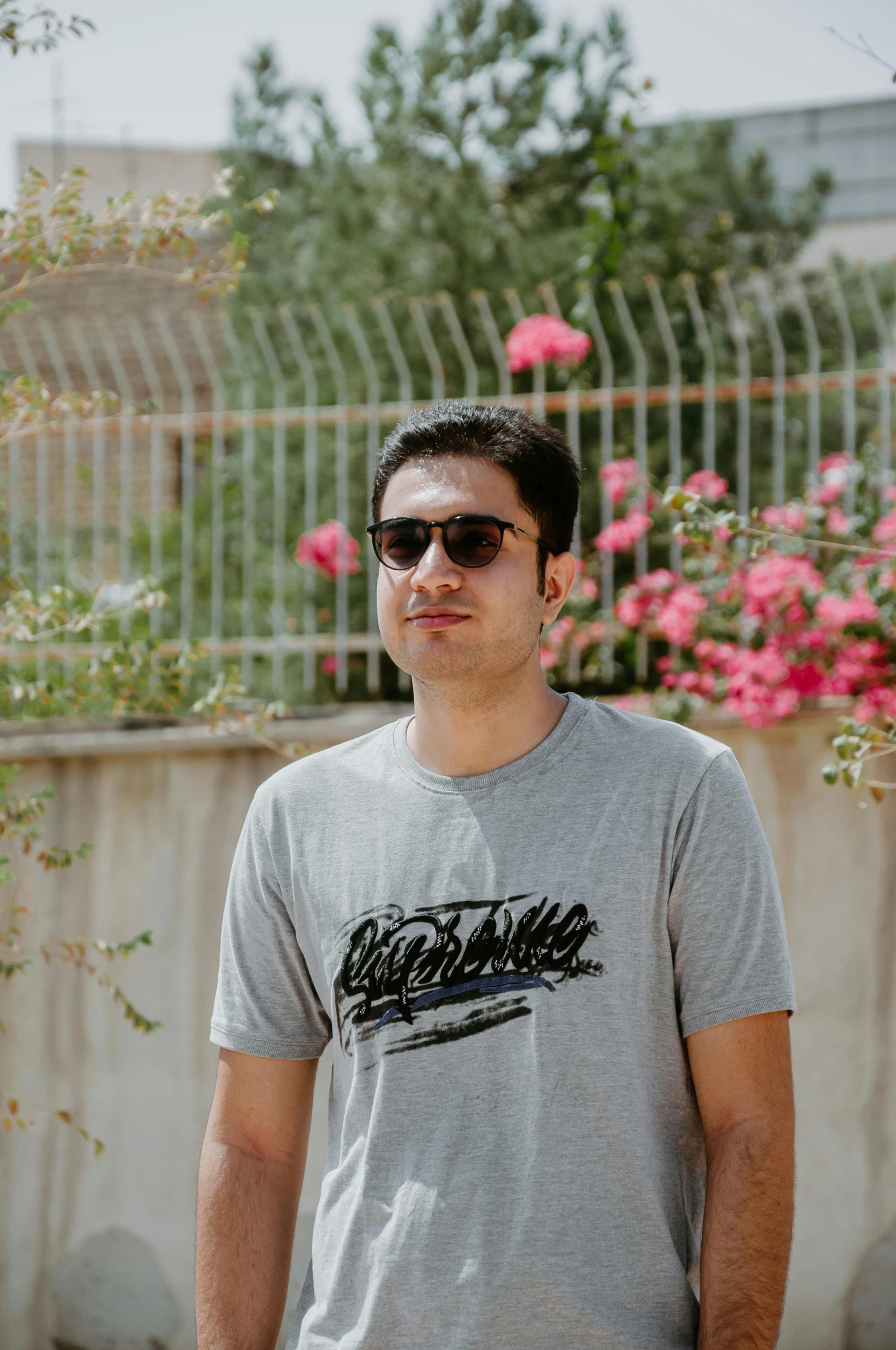 a guy is standing in front of flowers with his eyes closed