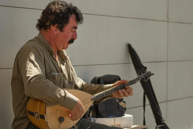 a man with a mustache plays the guitar outdoors