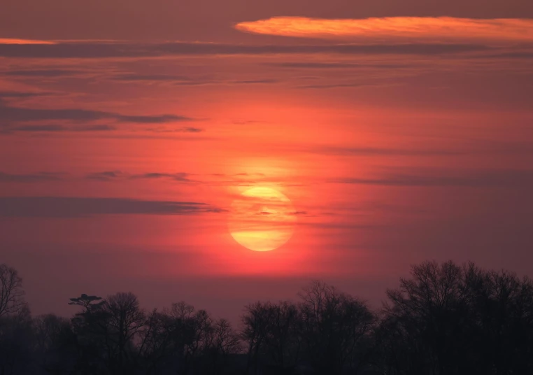 the sun is setting over the trees in the countryside