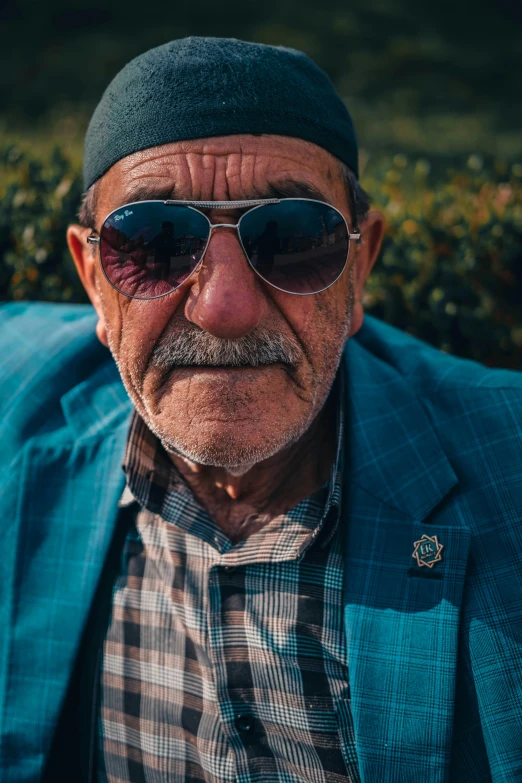 old man with beard wearing a suit, sunglasses and plaid shirt