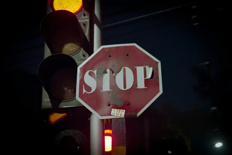 a stop sign with street lights above it at night