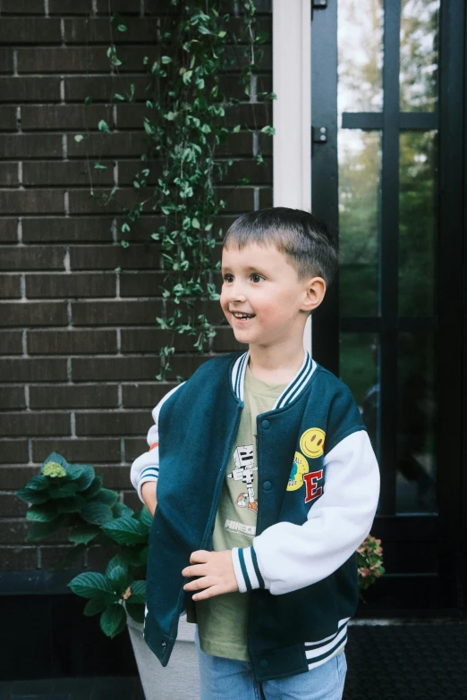 a small boy standing outside his house and smiling