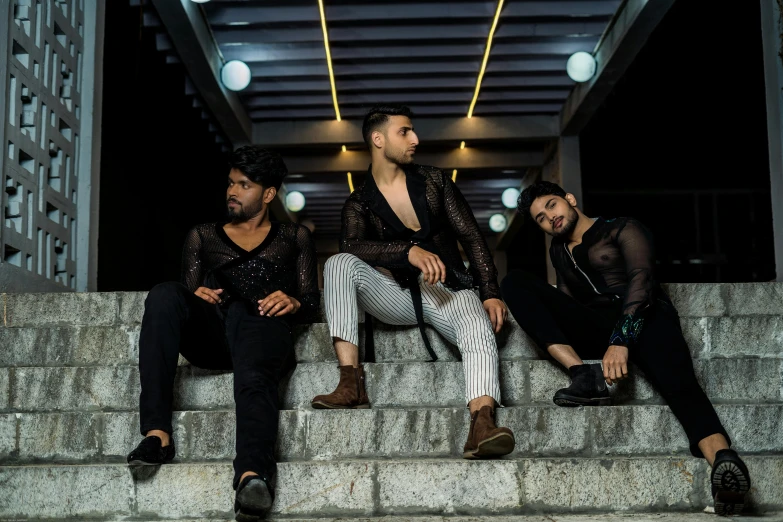 a group of three men in black sitting on steps