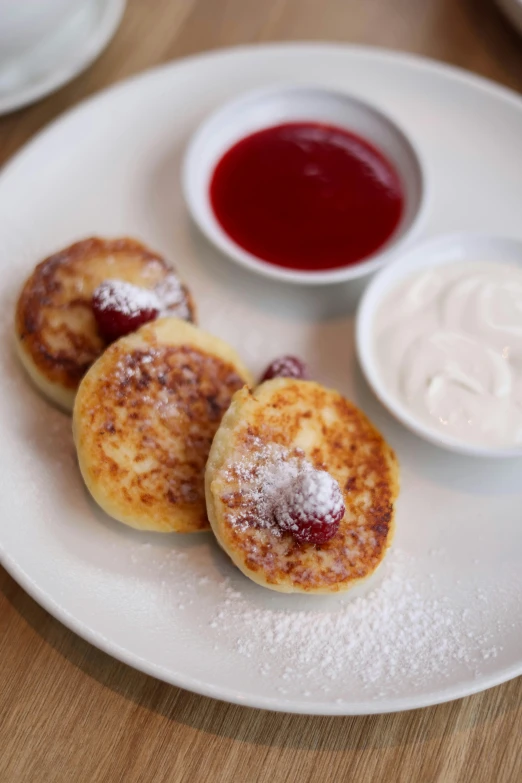 pancakes with powdered sugar on the side sit on a plate