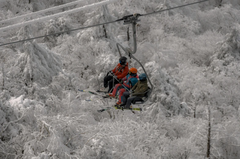 people sitting on a chairlift while one person is up in the ski lift