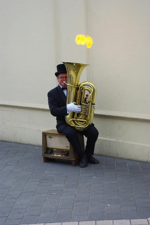 an individual dressed in a suit sitting on a suitcase holding a trumpet