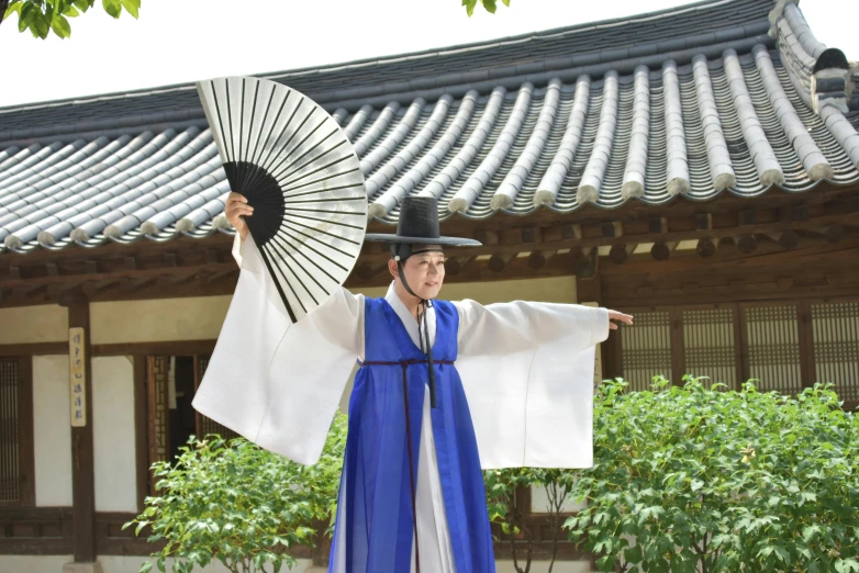 a man wearing a white and blue outfit holding an umbrella