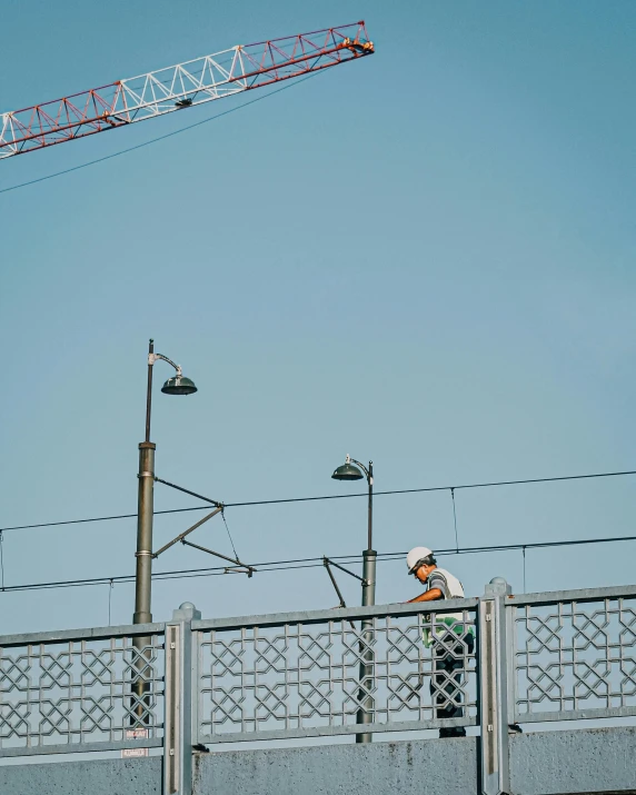 a crane is overhead and a man walks on a bridge