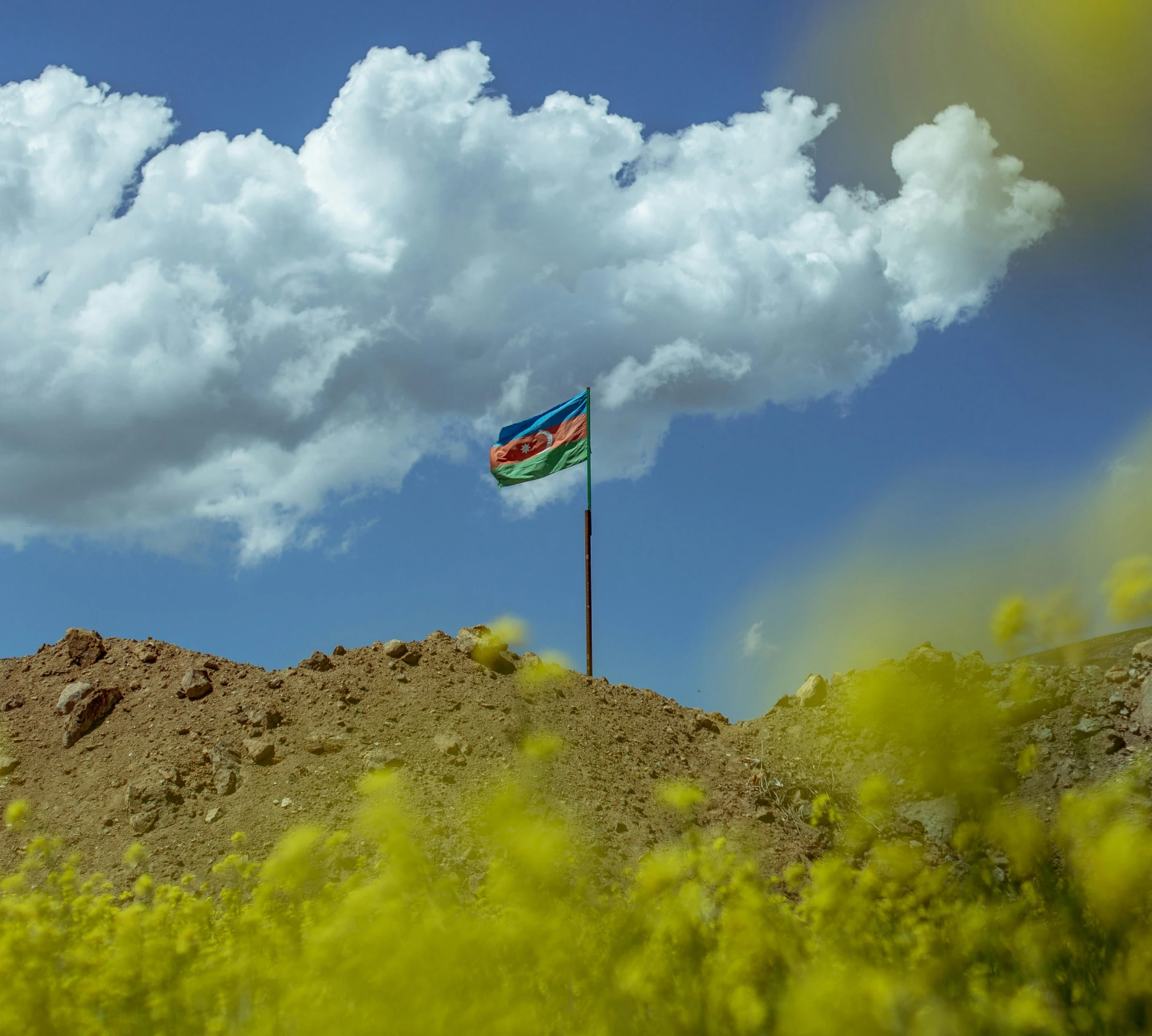 the small flag is flying on top of the rocky hillside