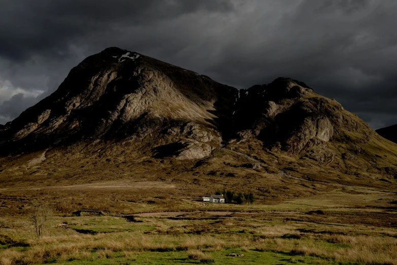 a small white house sitting under some very tall mountains