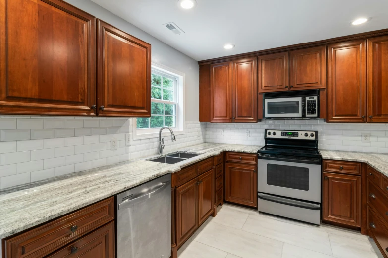 a kitchen has marble counter tops, hardwood cabinets and stainless steel appliances