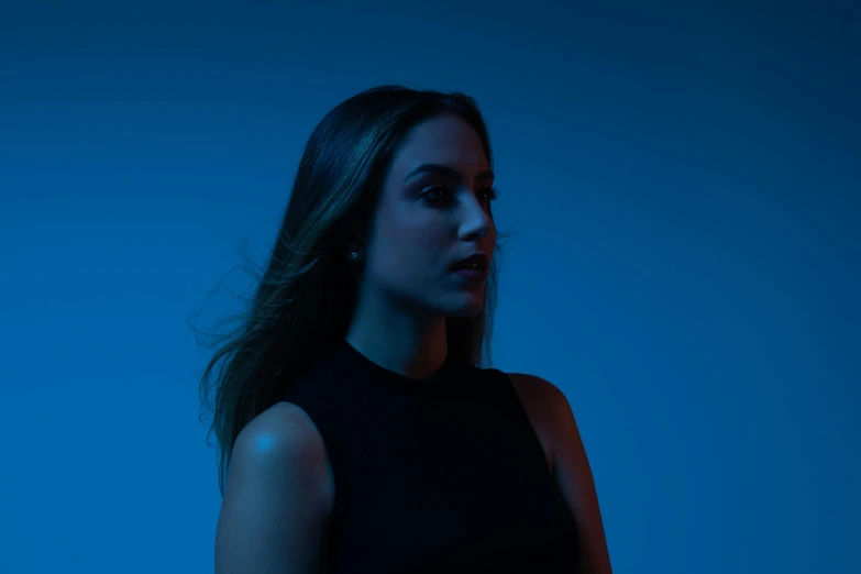 a woman wearing a black top against a blue background