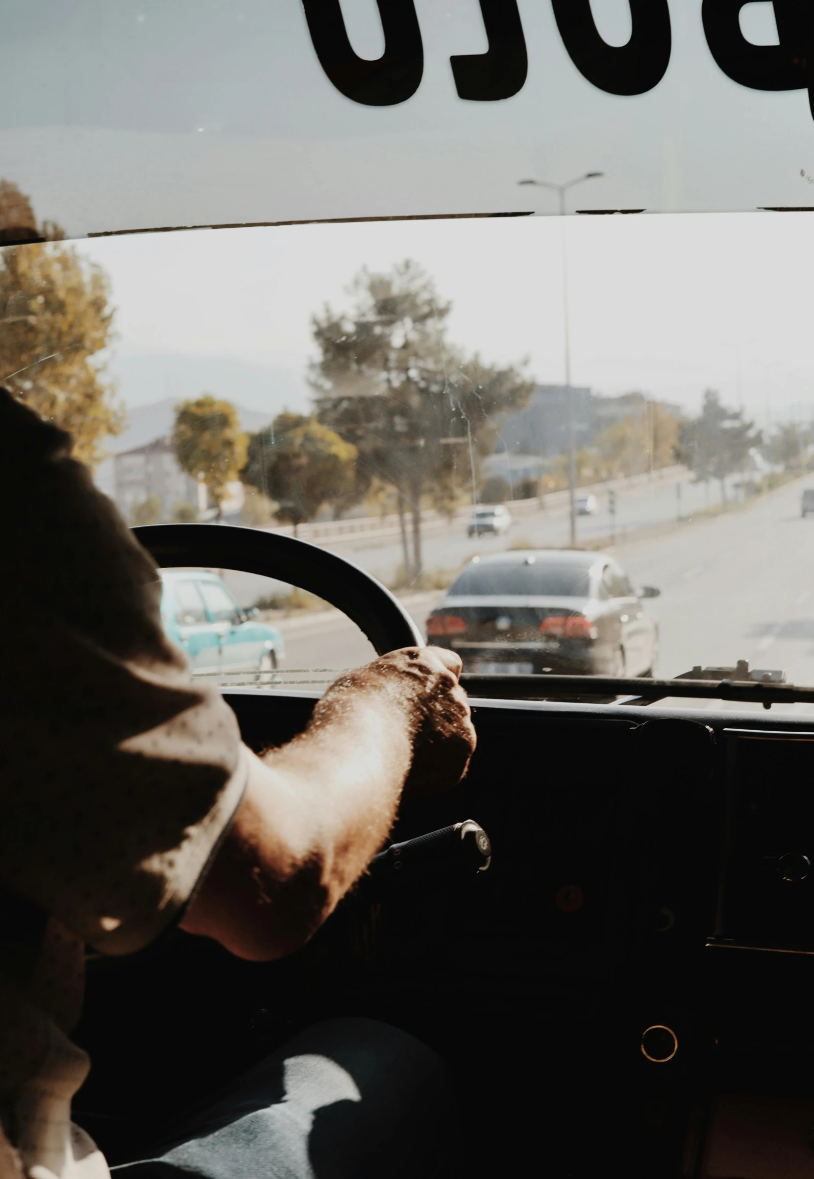 a person behind the wheel of a bus on the street