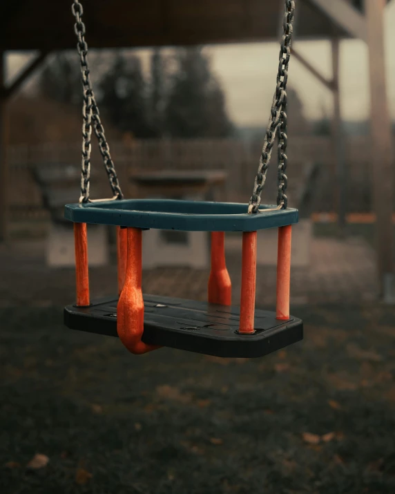 a child's swing in an empty park has wooden handles