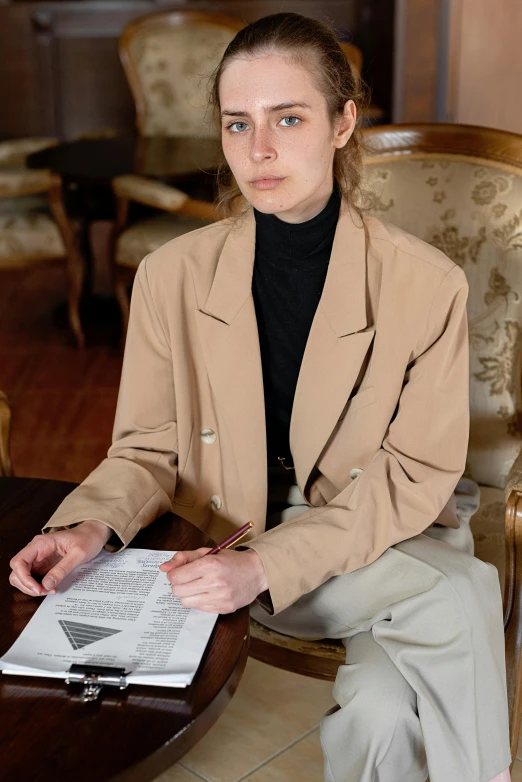 a young lady holding a paper while sitting in a chair