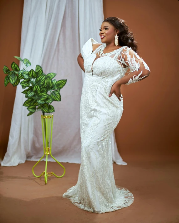 a woman is standing next to a plant with a bouquet in hand