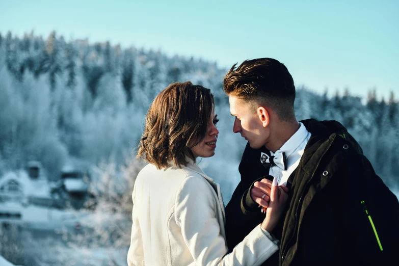 a man and woman standing close together in the snow