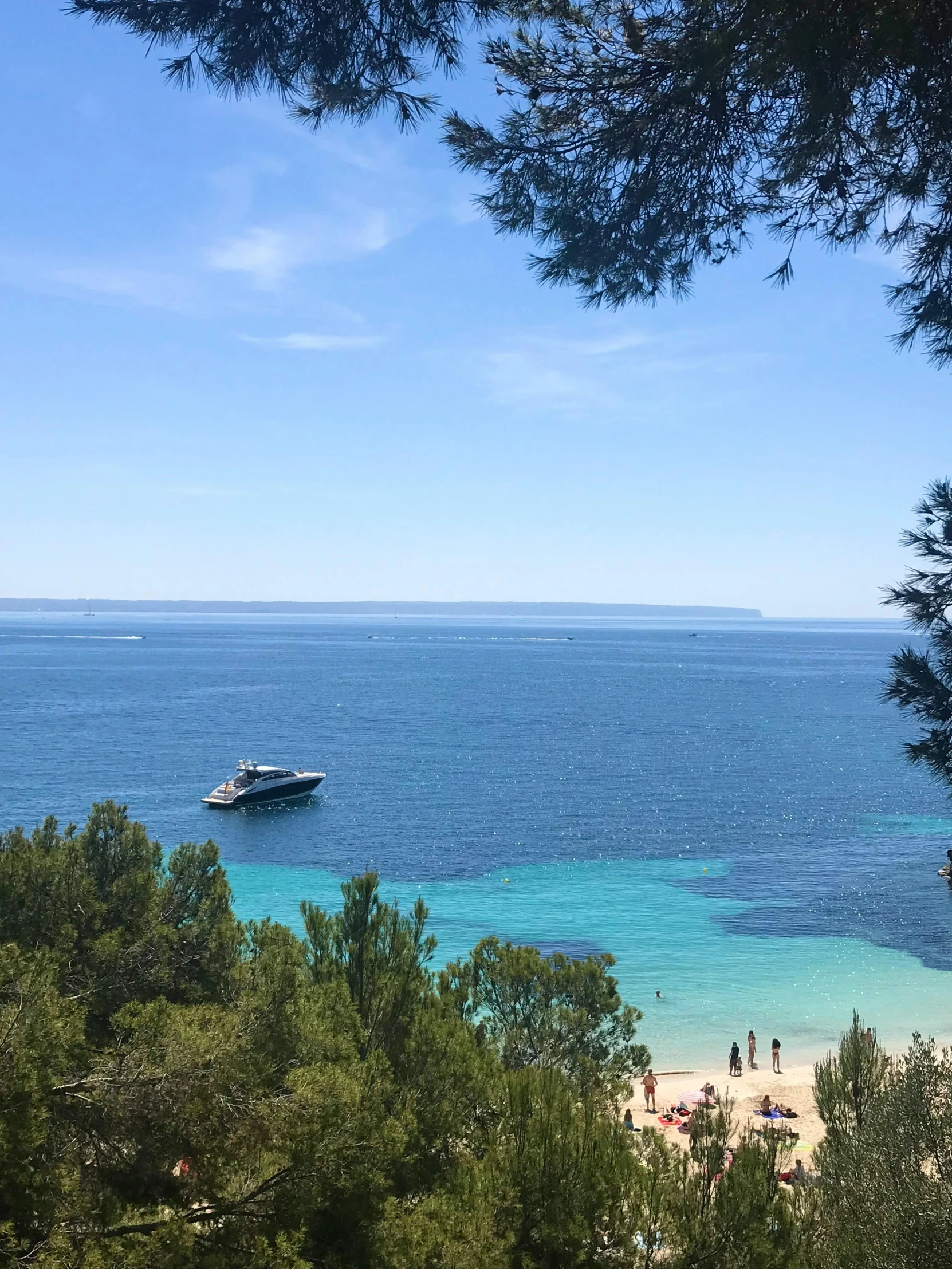 a beach area with people on the beach, a boat and water